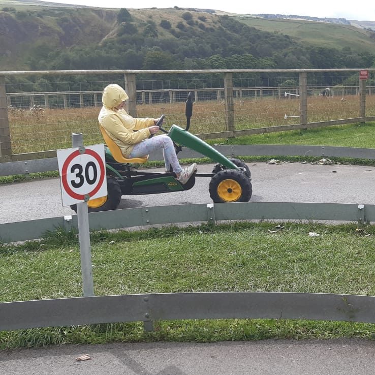 Child in a yellow jacket and blue helmet sledding down a snowy slope.
