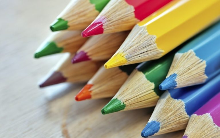 A collection of paintbrushes in a glass jar against a plain white background.