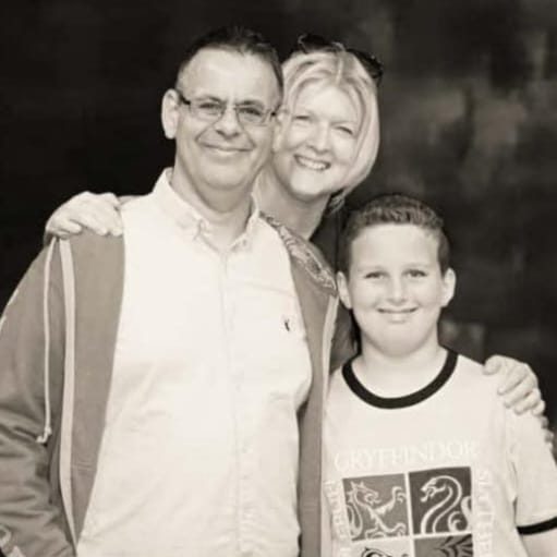 Julian, Judith and Son smiling together in a black and white portrait.