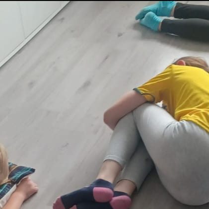 Children sitting on a floor, some curled up.
